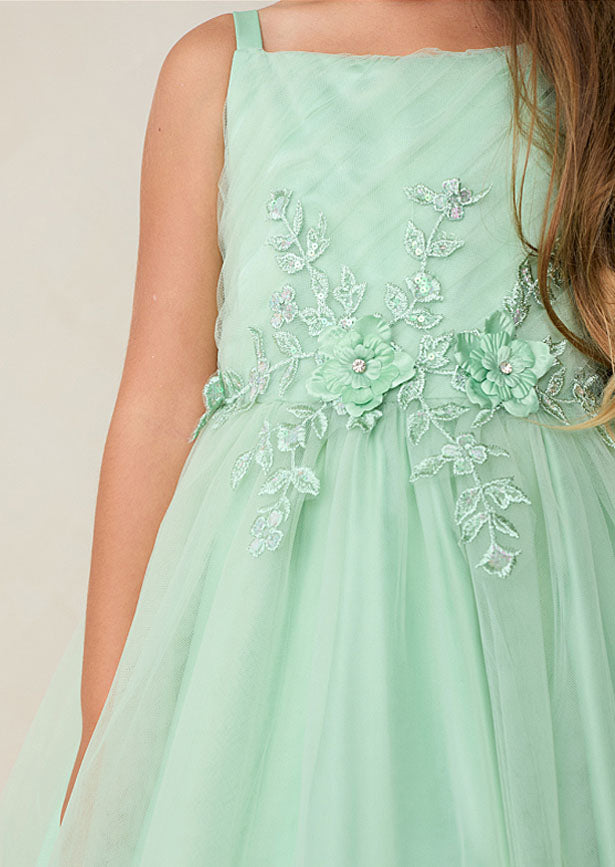 Crafted for the discerning eye, this floor-length girls sage green gown showcases a beautifully pleated bodice embellished with dimensional floral lace and shimmering iridescent accents