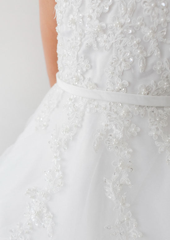  Mya Dress is designed for your daughter's most memorable moments. This stunning gown features a graceful V-neckline bodice adorned with delicate lace, shimmering sequins, and pearl embellishments. 