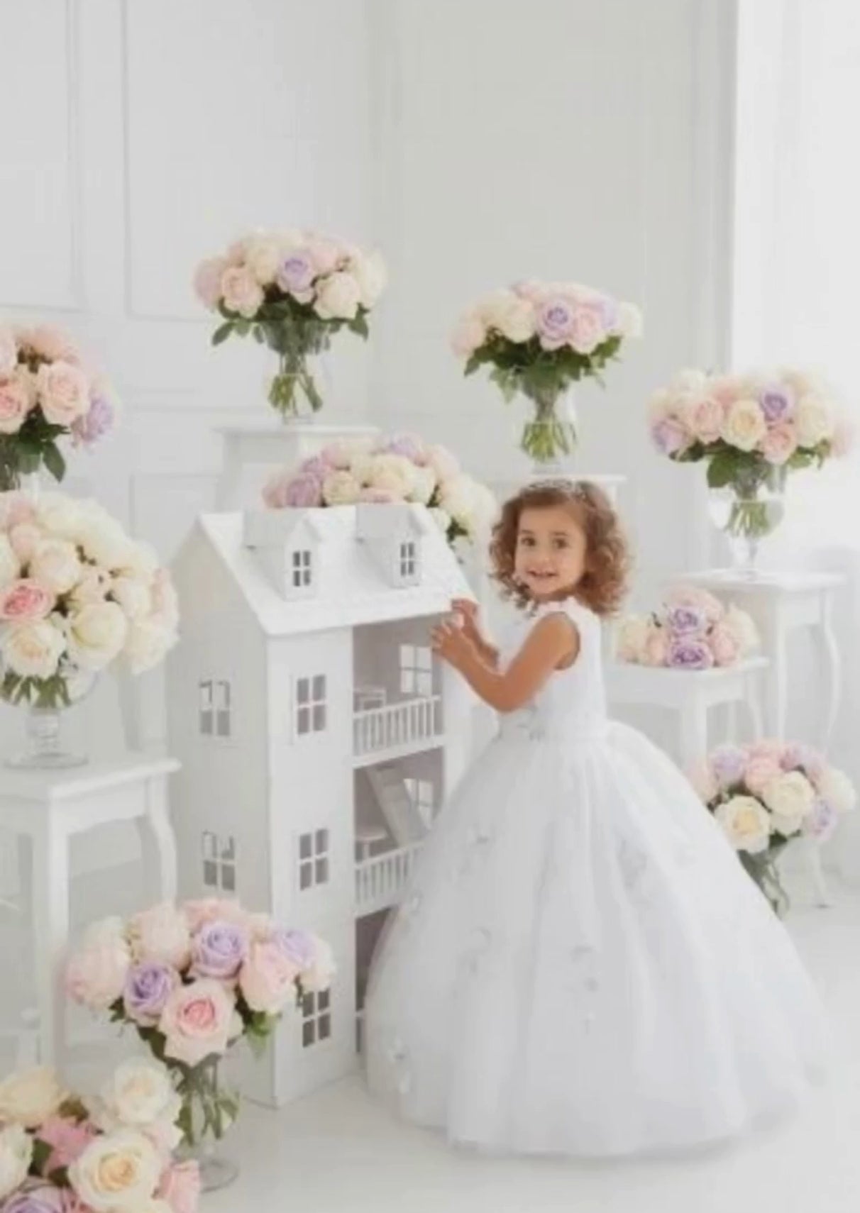 The Mia Belle Dress in White features an ornate floral bodice with glittering details and a mesh skirt adorned with flower appliqués